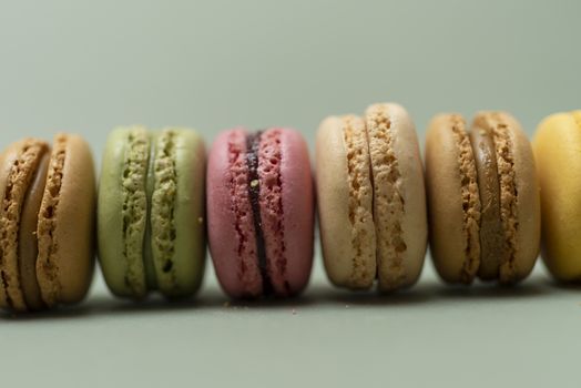 Assorted colored tasty macaroons over a green background.