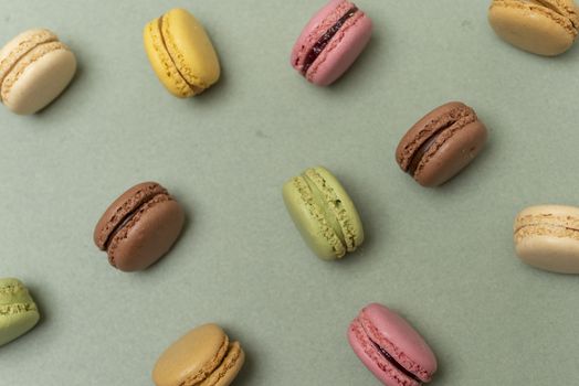 Assorted colored tasty macaroons over a green background.