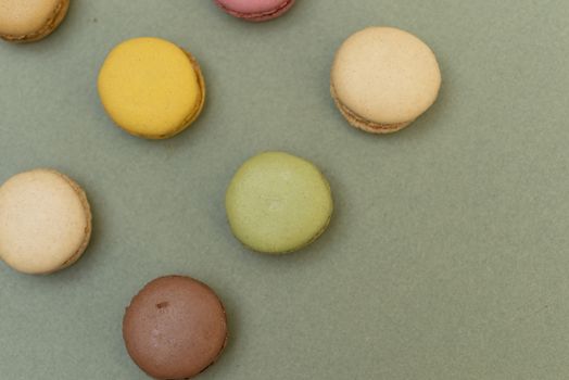 Assorted colored tasty macaroons over a green background.