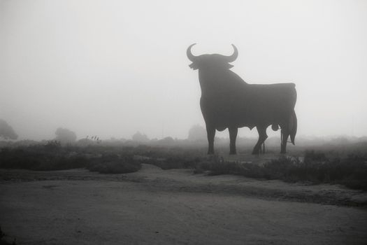 Santa Pola, Alicante, Spain- February 20, 2020: Silhouette of the mythical and typical spanish Osborne bull in the salt pans of Santa Pola, Alicante on a foggy day
