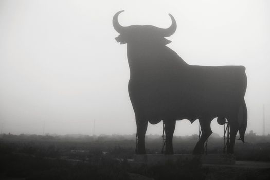 Santa Pola, Alicante, Spain- February 20, 2020: Silhouette of the mythical and typical spanish Osborne bull in the salt pans of Santa Pola, Alicante on a foggy day