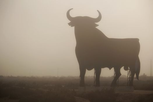 Santa Pola, Alicante, Spain- February 20, 2020: Silhouette of the mythical and typical spanish Osborne bull in the salt pans of Santa Pola, Alicante on a foggy day