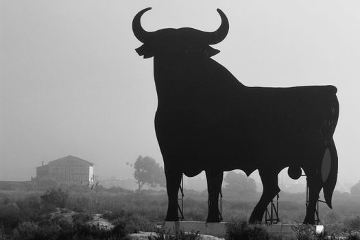 Santa Pola, Alicante, Spain- February 20, 2020: Silhouette of the mythical and typical spanish Osborne bull in the salt pans of Santa Pola, Alicante on a foggy day