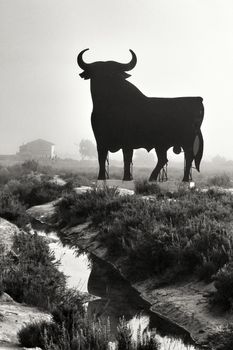 Santa Pola, Alicante, Spain- February 20, 2020: Silhouette of the mythical and typical spanish Osborne bull in the salt pans of Santa Pola, Alicante on a foggy day