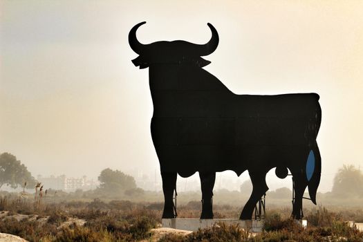 Santa Pola, Alicante, Spain- February 20, 2020: Silhouette of the mythical and typical spanish Osborne bull in the salt pans of Santa Pola, Alicante on a foggy day