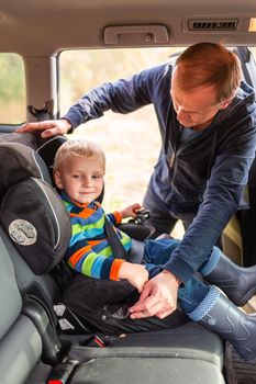 Father fastening safety belt for his baby boy in his car seat. Children's Car Seat Safety