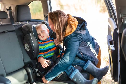 Mother fastening safety belt for her baby boy in his car seat. Children's Car Seat Safety