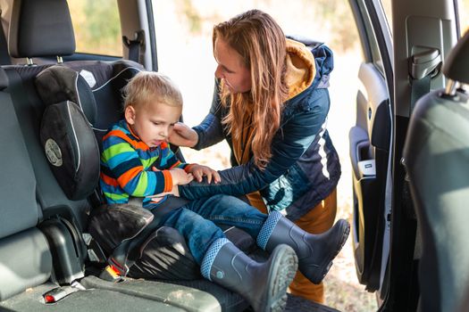 Mother fastening safety belt for her baby boy in his car seat. Children's Car Seat Safety