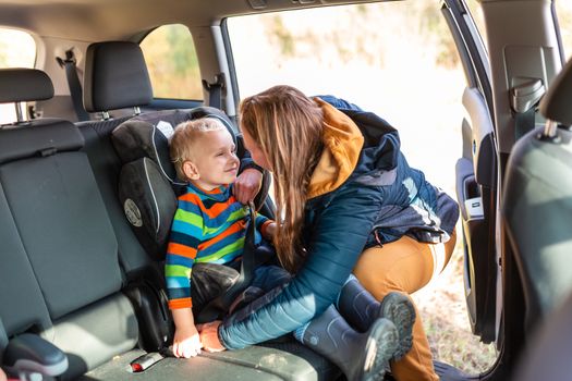 Mother fastening safety belt for her baby boy in his car seat. Children's Car Seat Safety