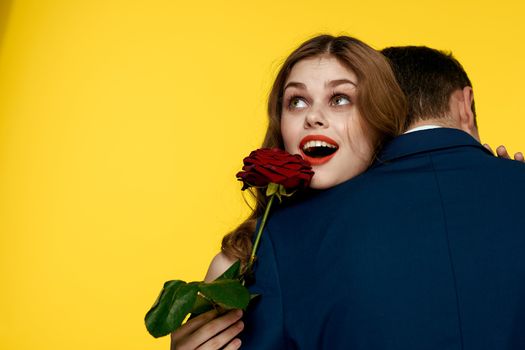 lovers man and woman with a red rose in their hands hugging on a yellow background romance relationship love family. High quality photo