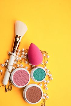 Eyeshadows and makeup brushes on a yellow background top view professional cosmetics. High quality photo