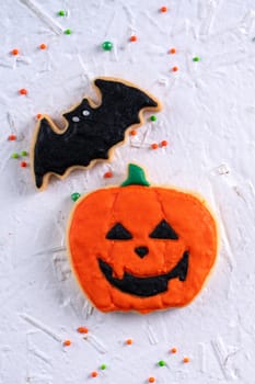 Top view of Halloween festive decorated icing gingerbread sugar cookies on white background with copy space and flat lay layout.
