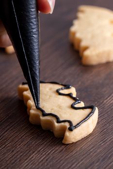 Close up of decorating cute Halloween bat gingerbread sugar cookies with frosting icing cream topping bag.