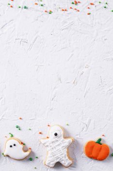 Top view of Halloween festive decorated icing gingerbread sugar cookies on white background with copy space and flat lay layout.