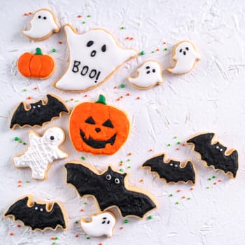 Top view of Halloween festive decorated icing gingerbread sugar cookies on white background with copy space and flat lay layout.