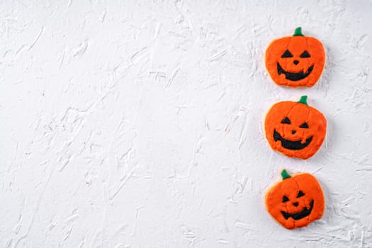 Top view of Halloween festive decorated icing gingerbread sugar cookies on white background with copy space and flat lay layout.