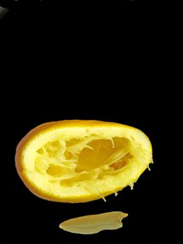 squeezed citron with juice on a black mirror