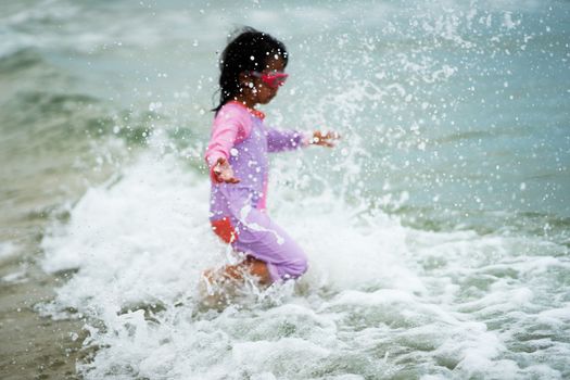 Girl play sea water at the beach with splash water in stop motion in beach vacation concept