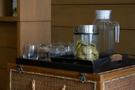 Glass bottle ,cup and cookies in jar in wooden tray for serving