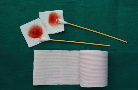tools include swabs,roll gauze and blood gauze on green surgical dress  for clean wound