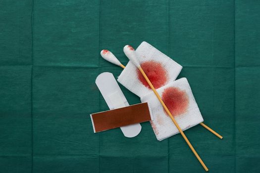 tools include plasters ,swab and blood gauze on green surgical dress  for clean wound