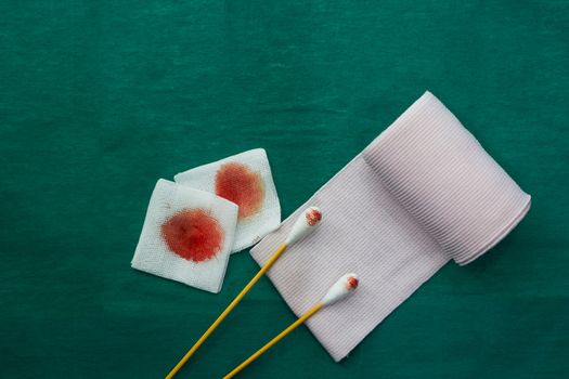 tools include swabs,roll gauze and blood gauze on green surgical dress  for clean wound with copy space