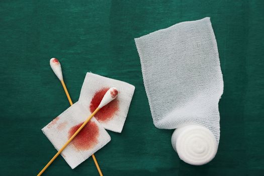 swab,blood gauze and roll gauze on green surgical dress ,tools for clean wound