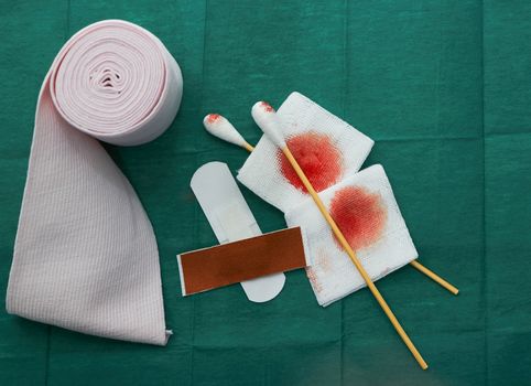 tools include plasters ,swab,blood gauze and roll gauze on green surgical dress  for clean wound