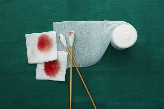 swab,blood gauze and roll gauze on green surgical dress for clean wound