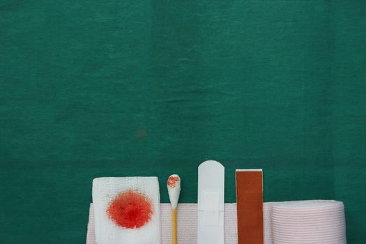 half tools includes plaster,swab,blood gauze and roll gauze on green surgical dress for clean wound with copy space