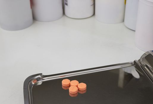 four orange medical tablets on half counting drug tray for drugstore