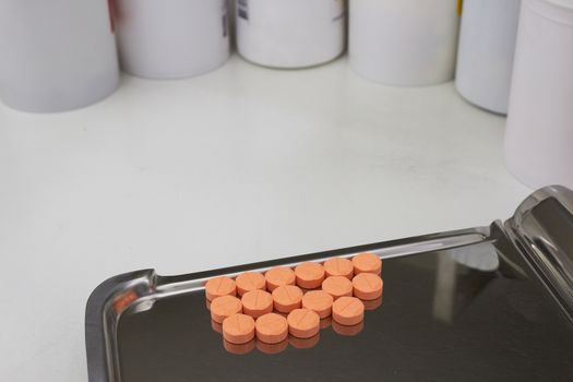 orange medical tablets on half counting drug tray for drugstore
