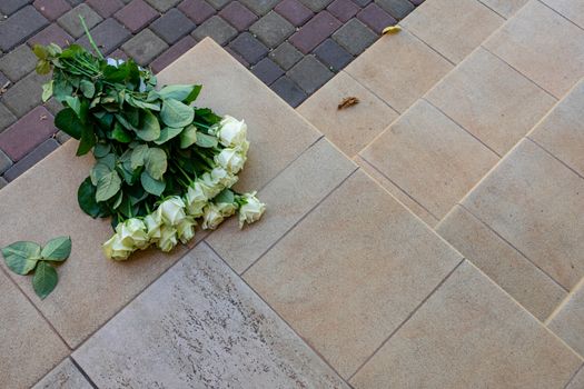 A bouquet of white roses was thrown on the ground