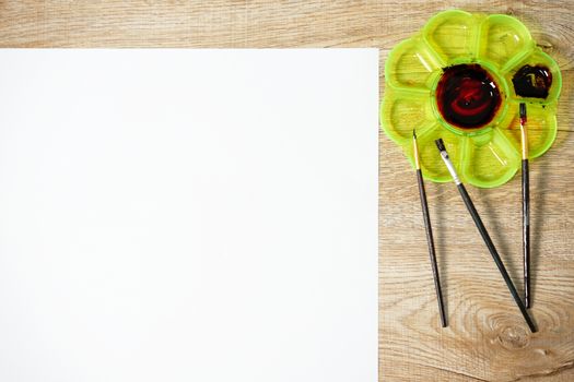 Paper of art work with color palette and brushes, top view