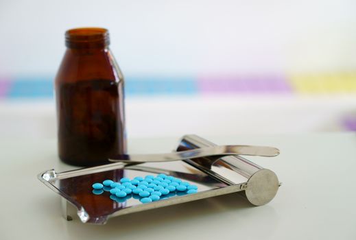pills counting tray with spatula and round coated medicine tablets and jar on blur background with copy space