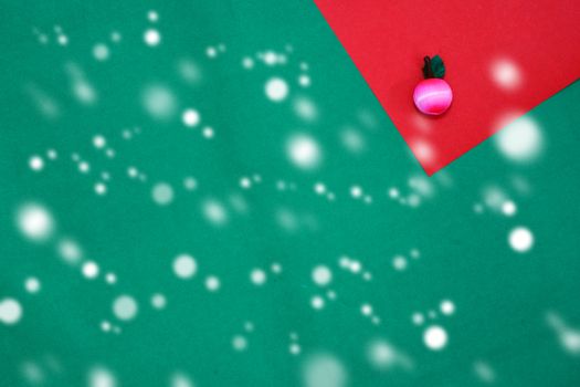 Pink fruit on red and green background with copy space for new year and christmas time with snow fall