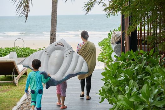 Travel family walk to the beach with toy floater in vacation concept