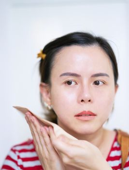 Woman in action of absorb or swept oil with paper on isolated white background