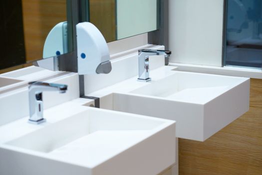 White ceramic sink and water tap with soap dispenser in bath room or toilet