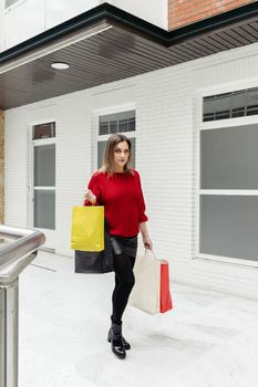 Adult woman walking through a mall with colorful shopping bags.