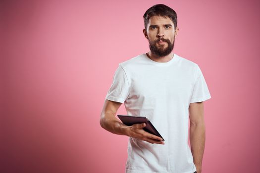 Man advertises a tablet on a pink background codes Space cropped view of emotions white t-shirt model new technologies. High quality photo