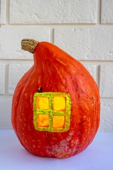 Pumpkin house with a window on a white brick background. The concept of Halloween ,harvest,thanksgiving,vegetarianism.