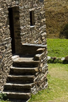 five stone stairs and entrance of an old village house and grass in the background