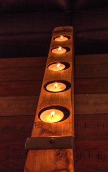 Rustic line of tea candles in a block of wood.