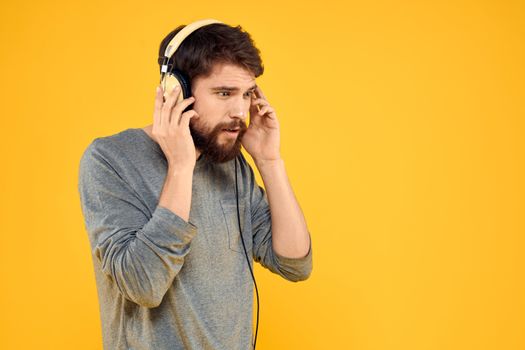 Man in headphones listens to music technology lifestyle fun people yellow background. High quality photo