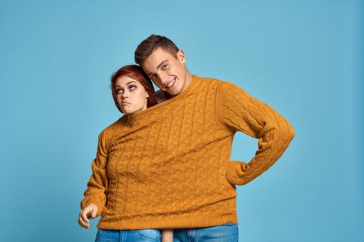 couple in yellow sweater posing against blue background cropped view. High quality photo