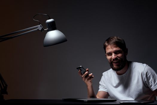 business man with mobile phone on dark background and iron lamp cropped view of work. High quality photo