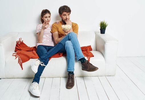 Couple in love with popcorn and watching TV while on the couch indoors. High quality photo
