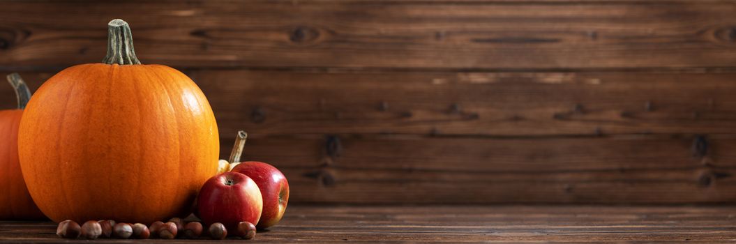 Wood background with pumpkin, apples and nuts. Copy space for text