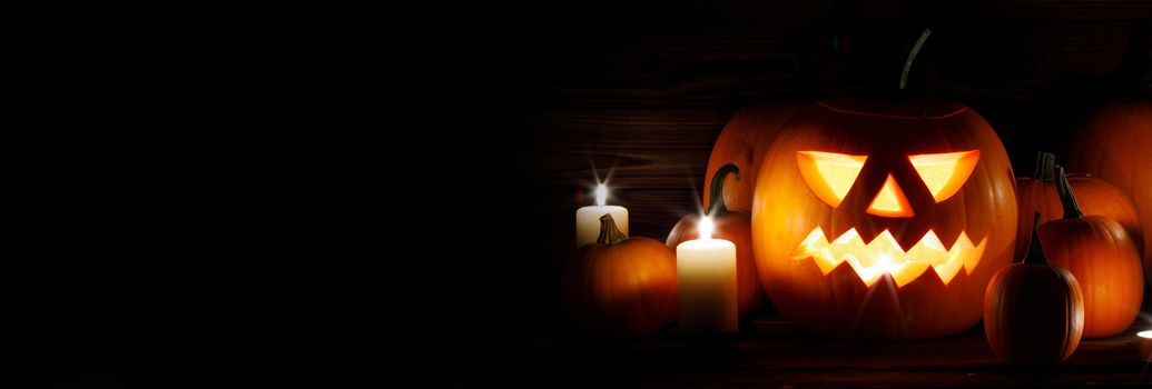 Halloween pumpkin head lanterns and burning candles on wooden background isolated on black